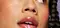 A close-up on a woman’s face. Her makeup includes bright yellow graphic eyeliner, flushed rouge cheeks, and plump lips