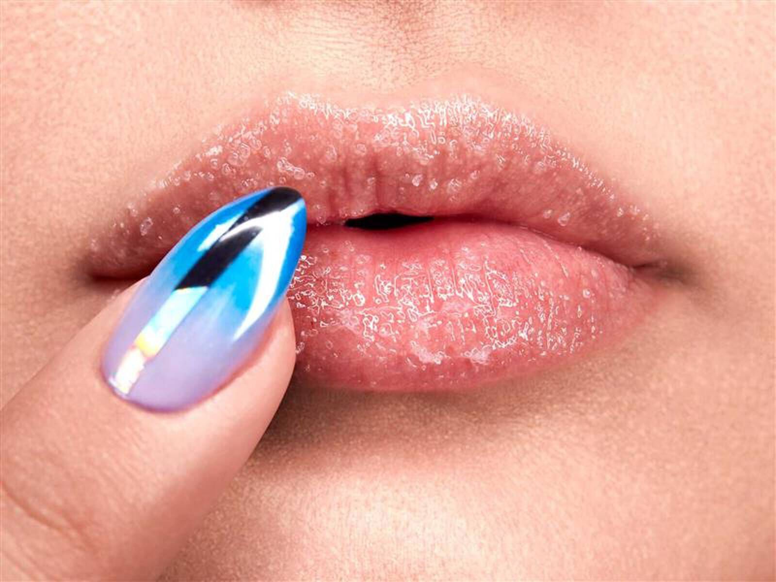 Close-up of a woman showing how to exfoliate lips using lip scrub