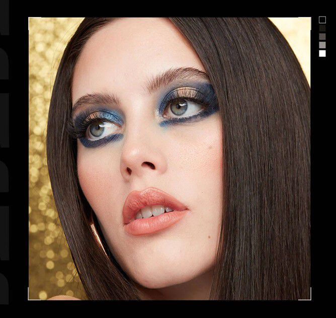 Close-up of a woman wearing stunning Christmas makeup with shimmery blue and gold eyeshadow