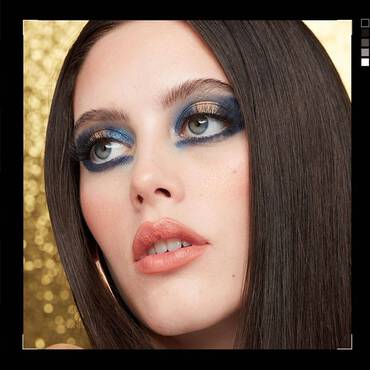 Close-up of a woman wearing stunning Christmas makeup with shimmery blue and gold eyeshadow
