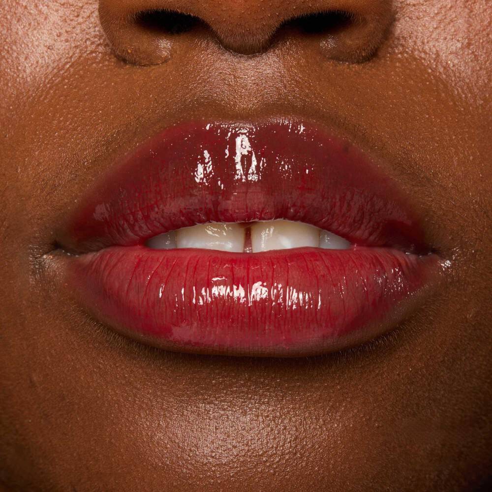 Close-up of hands applying lip gloss, demonstrating tips on how to apply lip gloss.