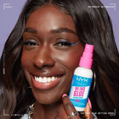 A woman applying a setting spray on her face after finishing her makeup