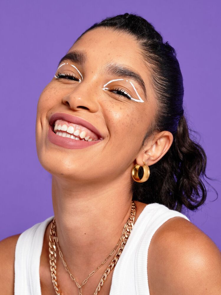 A smiling woman wears NYX’s Epic Wear Liquid Eye Liner in white.