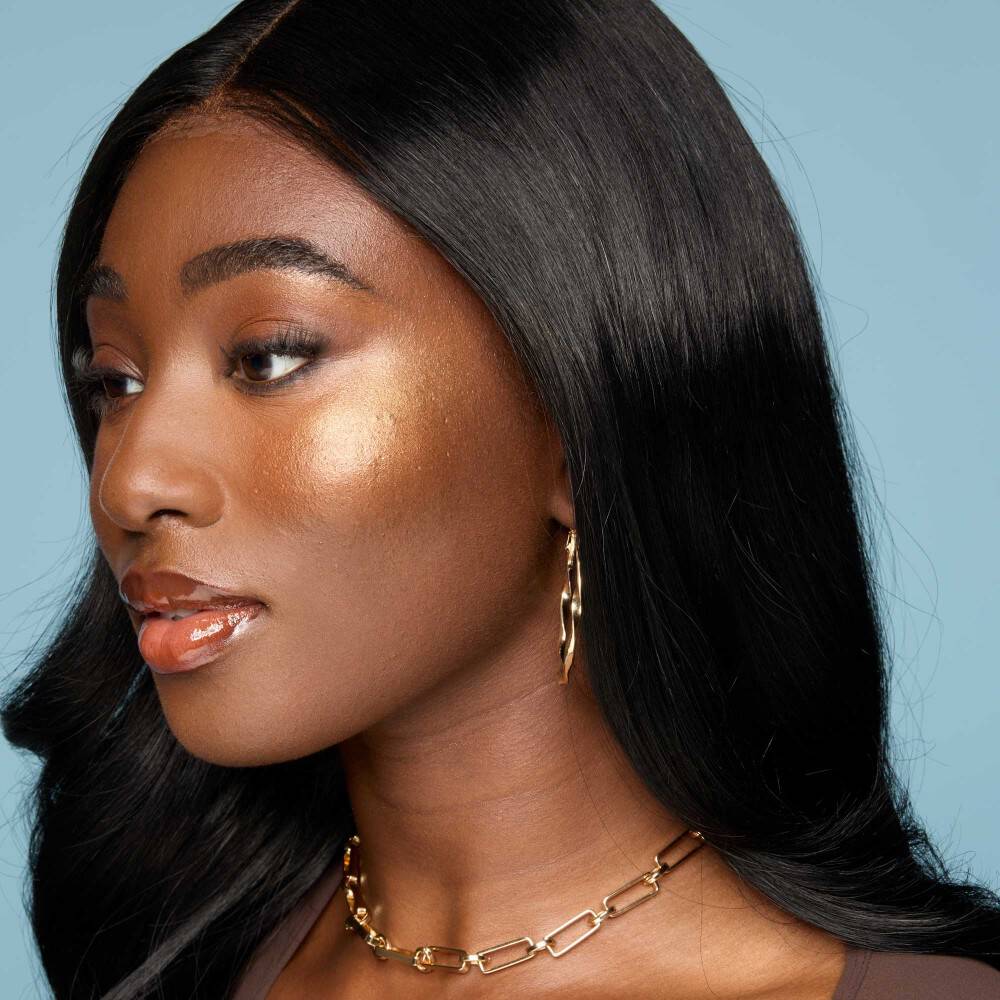 Model after applying highlighter to cheekbone for a glowing makeup look, demonstrating where to apply highlighter and how to use highlighter on the face.